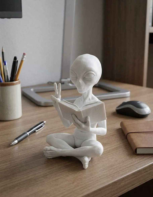 Alieno con Libro — Statuetta da Collezione in ResinaUn piccolo visitatore da un altro mondo con la testa sempre tra le pagine.L'Alieno con Libro porta ironia e mistero intergalattico sulla tua scrivania: libro in manoTarafloTarafloAlieno con Libro