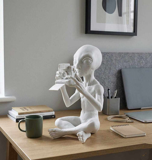 Alieno con Fotocamera Polaroid — Statuetta da Collezione in ResinaUn piccolo visitatore da un altro mondo che non si perde un solo momento.L'Alieno con Fotocamera Polaroid porta ironia e mistero intergalattico sulla tua scrivania: TarafloTarafloAlieno con Fotocamera