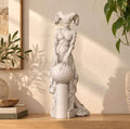 Statua di Lilith effetto gesso bianco: figura gotica con grandi corna d'ariete e mani su una sfera, su mensola in legno