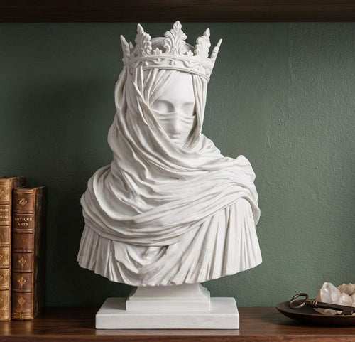 Busto bianco effetto gesso di regina velata con corona su mensola in legno tra libri antichi e cristalli