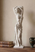 Statua bianca effetto gesso di figura femminile bendata con braccia alzate su mensola in legno accanto a libri antichi