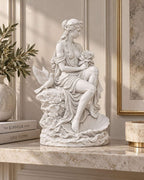 Statua di Venere effetto gesso bianco distesa su conchiglia con rosa, accanto a libri e rami decorativi