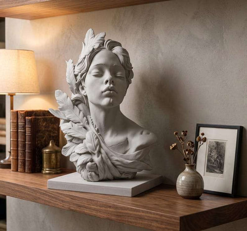 Busto in gesso bianco di figura femminile con foglie su mensola in legno accanto a libri