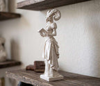 Vista laterale della statua gotica bianca con corna e abito vittoriano che sfoglia un libro