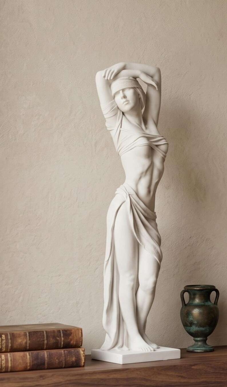 Scultura bianca di donna drappeggiata con occhi bendati, stile classico, su mensola con libri