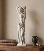 Statua femminile bianca effetto gesso con benda sugli occhi affiancata da libri e vaso metallico