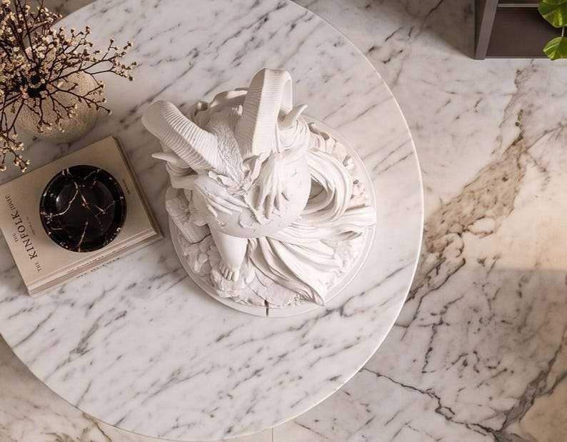 Vista dall'alto della statua bianca con corna su tavolino di marmo accanto a libri e rami secchi