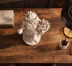 Statua di Persefone vista dall'alto su scrivania in legno accanto a libri e portapenne